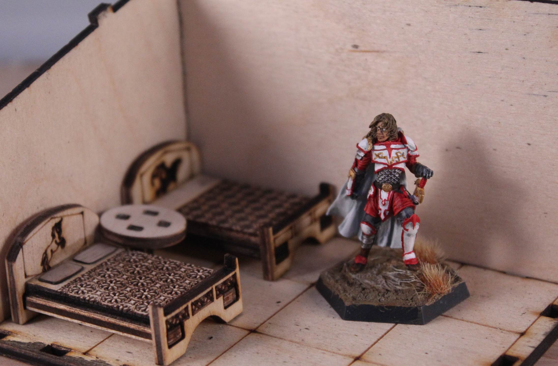 One miniature figurine shown in the interior of the house with beds and nightstands placed on their one inch squares.